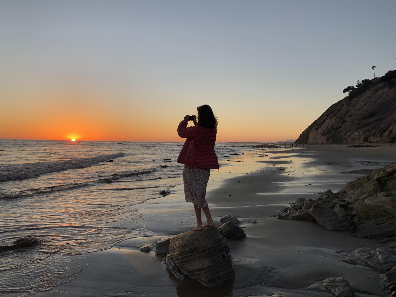 Person taking a photo of a breathtaking sunset while standing on a rock near Channel Islands National Marine Sanctuary.