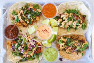 An overhead photo of a four-taco tray at Mid East Tacos in Silver Lake, sauces and lime wedges in the middle
