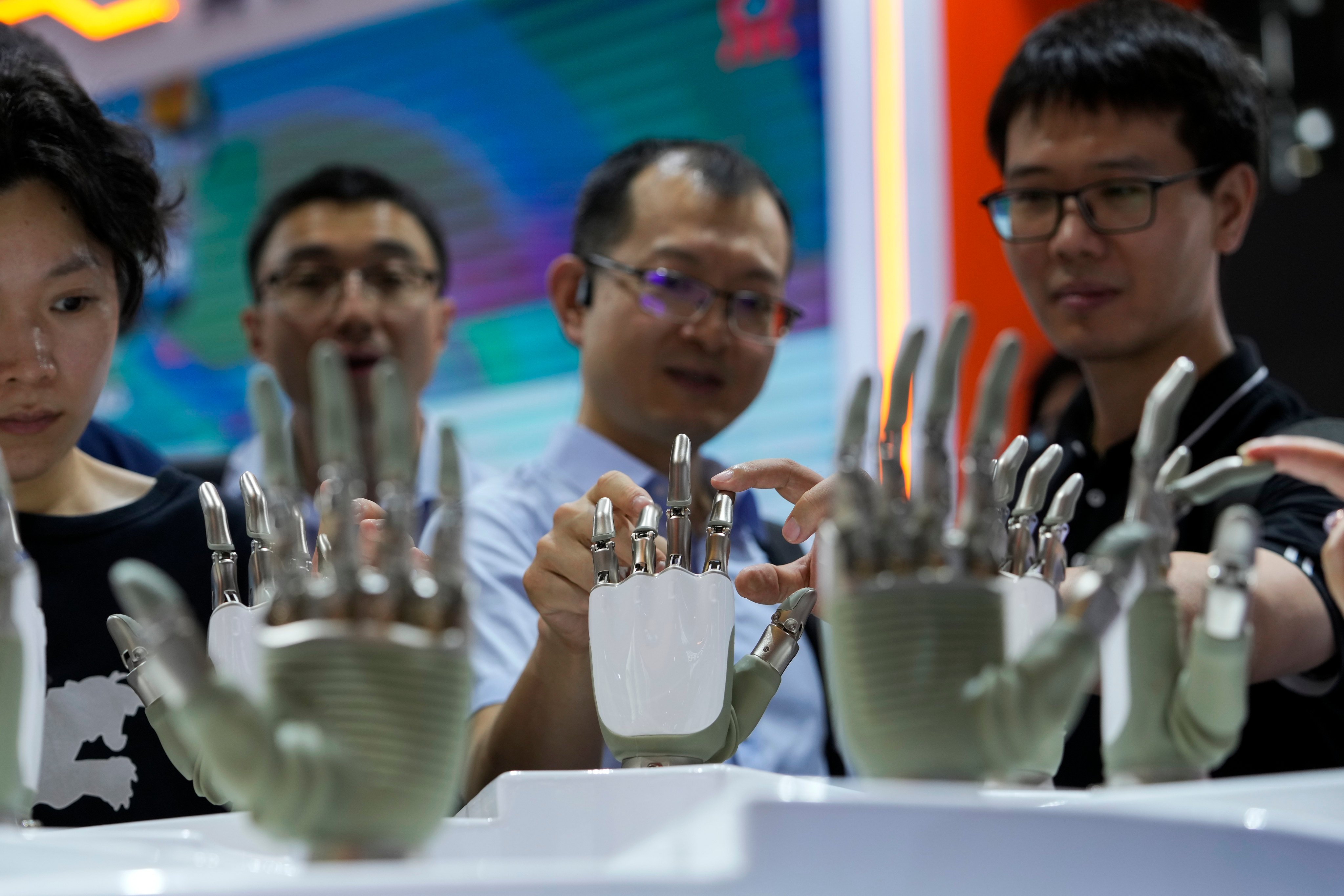 Visitors touch the humanoid robot hands on display at a booth during the World Artificial Intelligence Conference (WAIC) in Shanghai China, July 4, 2024. Photo: AP