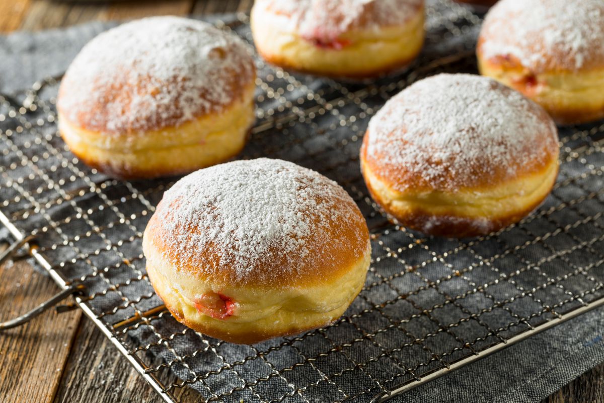 Polish paczki donuts with jelly filling on a drying rack.