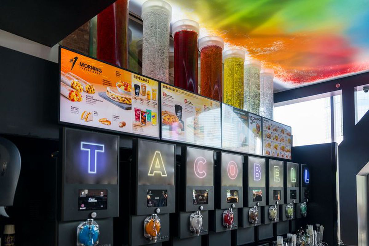 A row of Twisted Freeze machines at a Taco Bell Cantina, featuring brightly colored liquids and neon accents