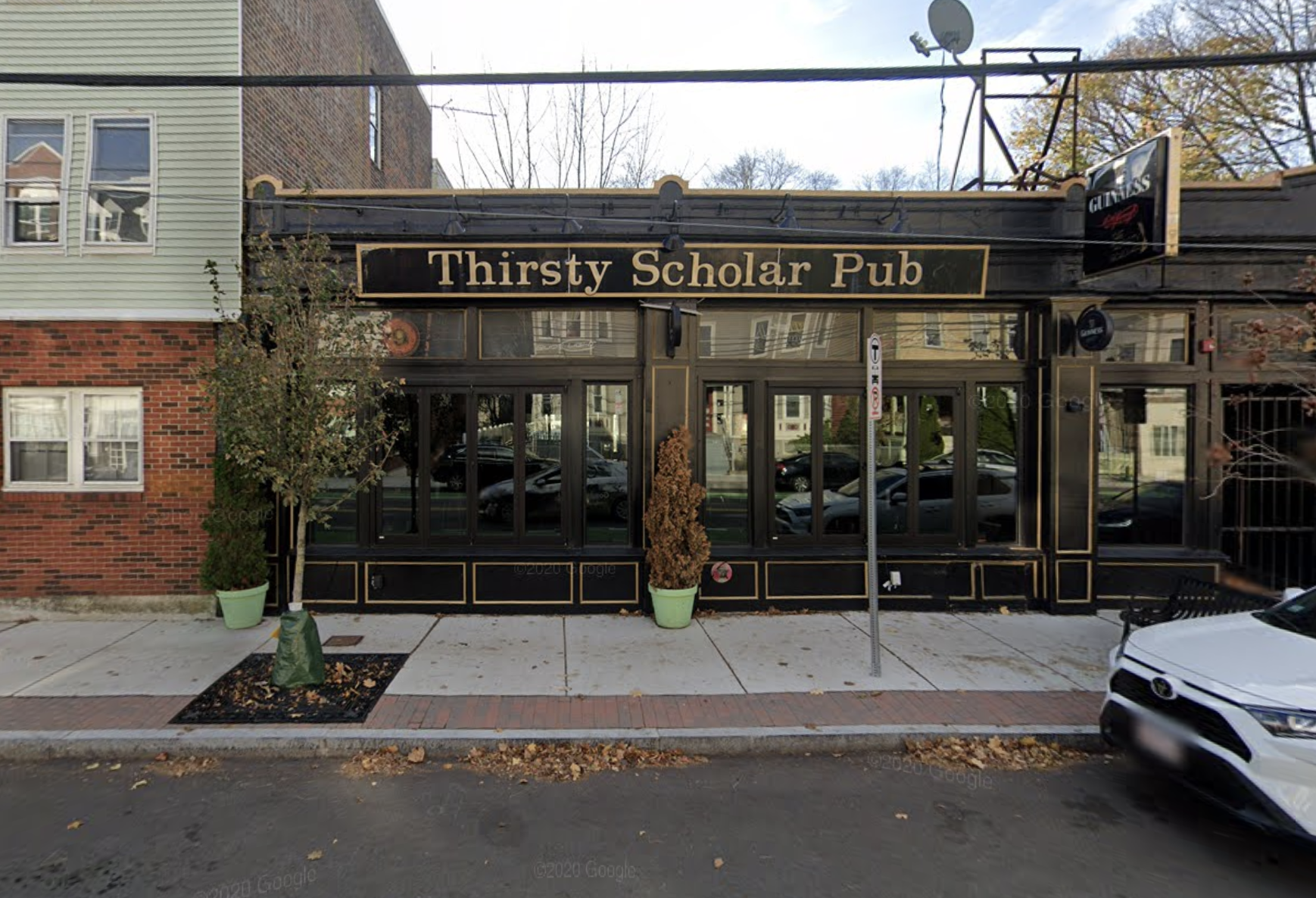 A bar exterior with a black and gold sign that reads “Thirsty Scholar Pub.”