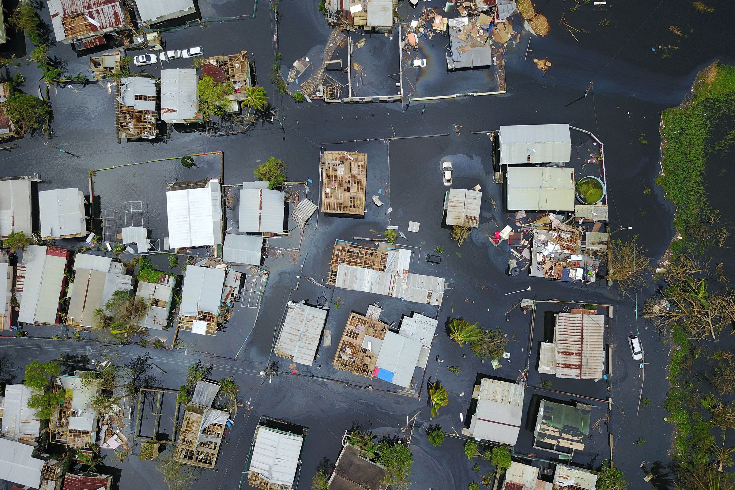 An aerial view shows the rooftops of homes and buildings in a flooded area.
