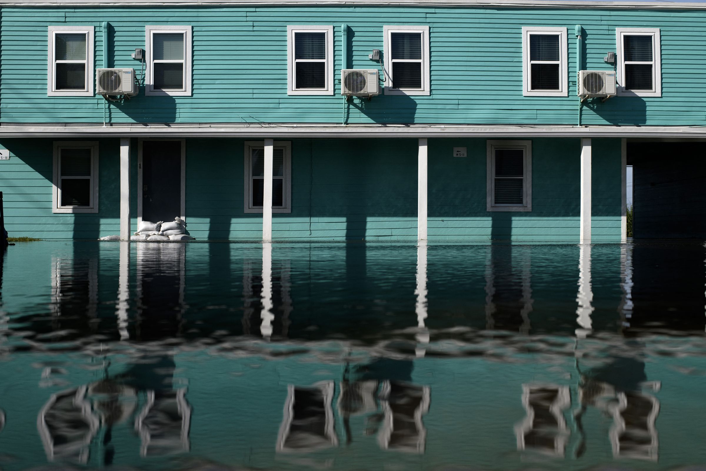 Air conditioning units amid a row of windows in a motel rising above floodwaters.