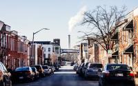 Smokestacks in the background of a neighborhood with rowhouses in Baltimore, MD