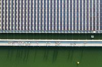 People walk along a bridge next to rows of floating solar panels.