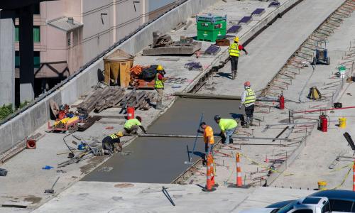 Cement and concrete workers focus on a section of a bridge.