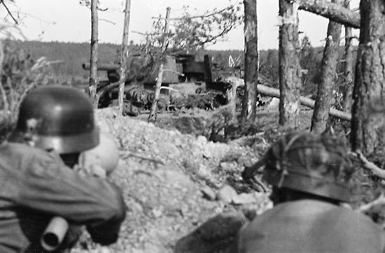 In the background, a Russian KV2 assault vehicle destroyed by Finnish anti-tank fire (foreground) at a crossroads between Ihantala and Karisalmi.