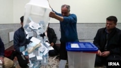 Election workers empty a ballot box in Iran's presidential election. 