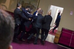 Police officers carry a pro-Serb opposition lawmaker in the parliament building in Podgorica, Montenegro, Dec. 27, 2019.
