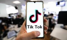 A man holding a smartphone displaying the logo of TikTok.