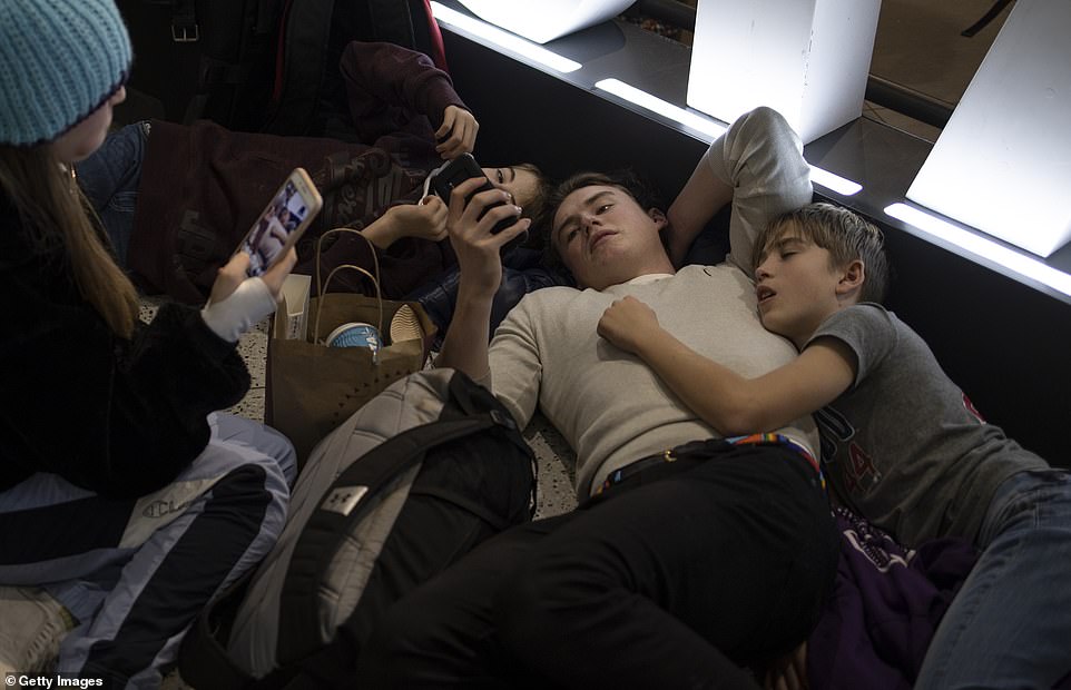 A group of youngsters watch something on their phones as one young man gets some sleep as up to 760 flights were suspended yesterday 