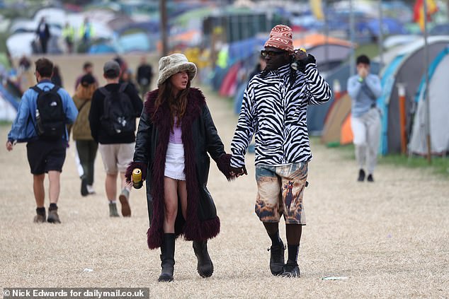 Revellers walk through the Glastonbury Festival site at Worthy Farm in Somerset this morning