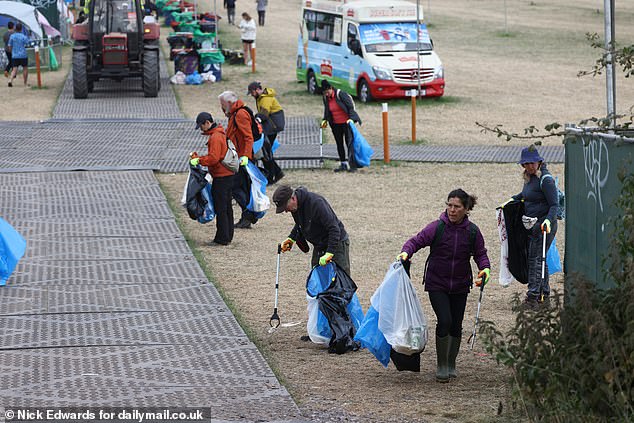 People collect rubbish at the Glastonbury Festival this morning ahead of the artists playing