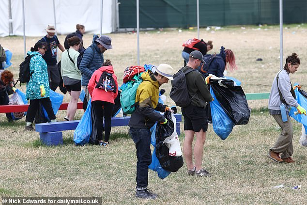 People collect rubbish at the Glastonbury Festival this morning ahead of the artists playing