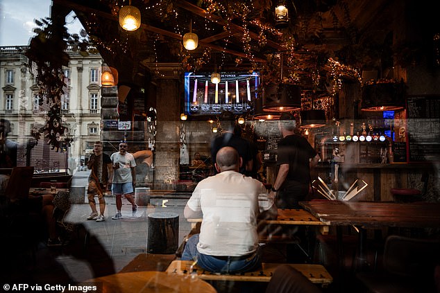 A man watches on a television the results of the first round of the legislative election in a bar in Lyon, on June 30, 2024