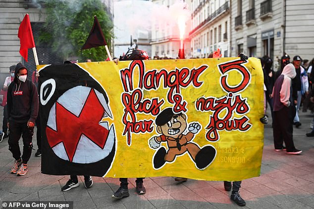 Demonstrators hold a banner reading "eat five cops and nazis a day" as they take part in a rally after the announcement of the results of the first round of parliamentary elections in Nantes
