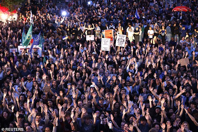 Demonstrators raise their arms as they gather to protest against the French far-right National Rally party