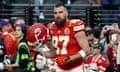 Travis Kelce at the Super Bowl LVIII pregame holds his helmet and stares at the camera in a soft but also well hard way.