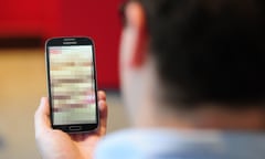A man looking at a mobile phone with its screen pixellated