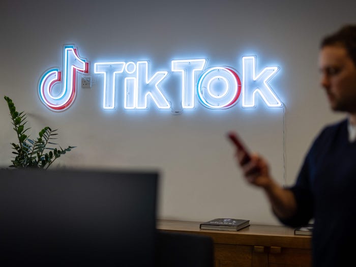 BuzzFeed News reported Monday that TikTok's owner ByteDance had scraped content from Instagram and Snapchat in 2017 to create fake accounts on Flipagram, TikTok's predecessor. Here, a TikTok employee looks at his mobile phone as he walks past the logo of TikTok in a London office on February 9, 2022.