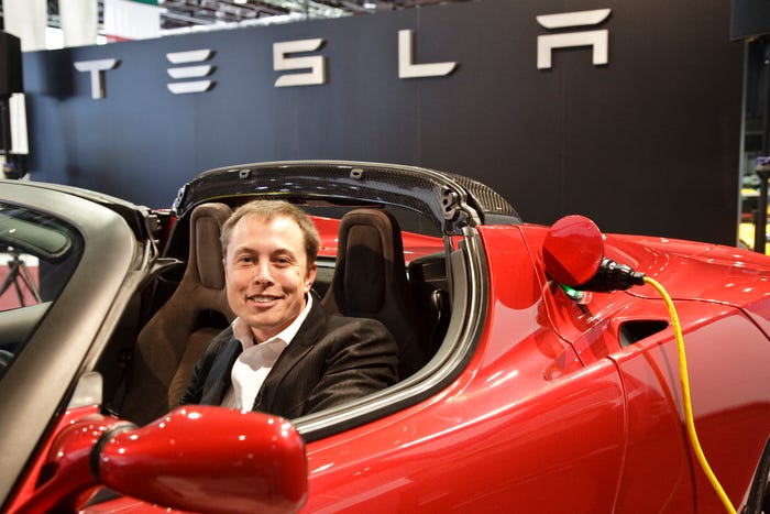Elon Musk in a red Tesla Roadster.