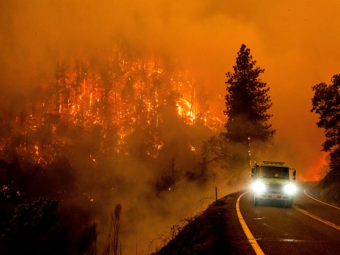 A firetruck drives along a California highway as the McKinney Fire burns