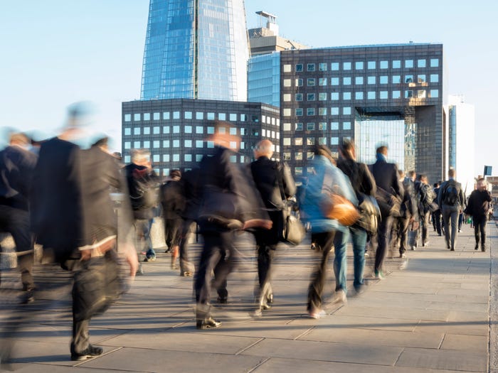 Blurred image of business commuters crossing London Bridge, office buildings with The Shard are visible in the background, London, England