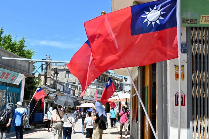 This photo taken on August 11, 2022 shows Taiwanese flags on a street lane as tourists walk past in Taiwan's Kinmen islands.