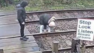 Young people on a railway line level crossing, shown on CCTV