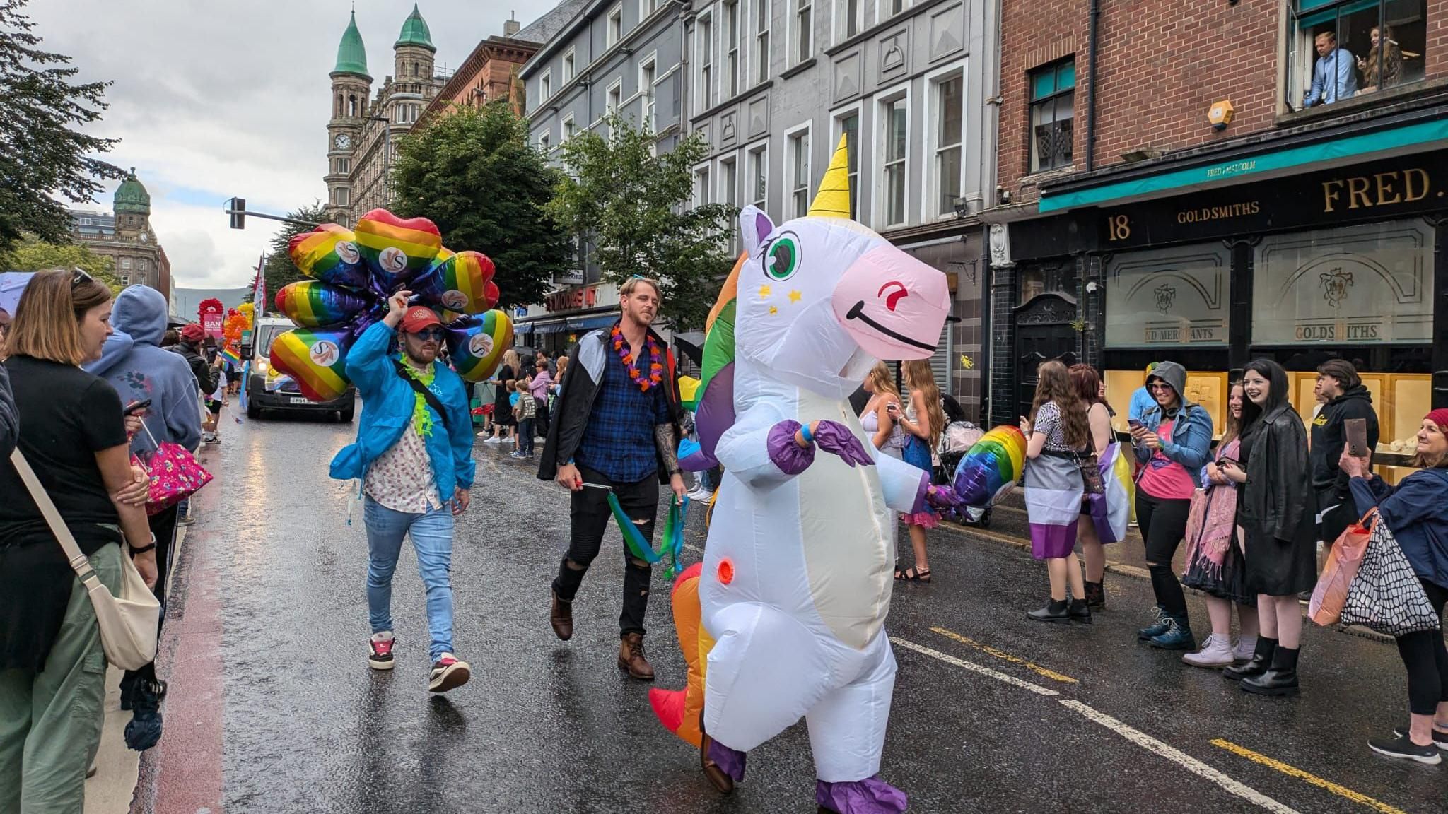 Person dressed in an inflatable unicorn costume walking in the parade