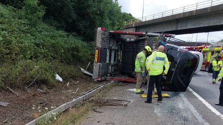 Police officers next to an overturned car and lorry cab