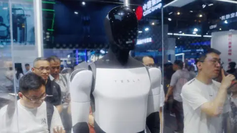Getty Images Visitors look at Tesla humanoid robot on display at an AI conference in China.