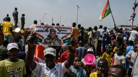 Getty Images Protesters in Niger waving flags and holding pictures of the
