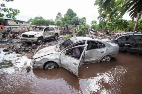 Reuters Dented and smashed cars litter the flooded streets with palm trees in the background