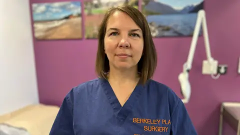 Head and shoulders shot of Dr Olesya Atkinson in blue scrubs with her name on
