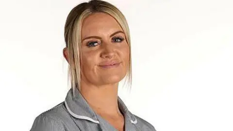 A woman with blonde hair in a nurse's outfit smiling 