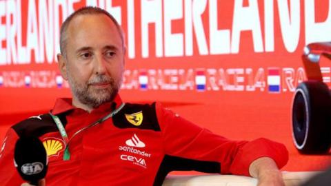 Ferrari director Enrico Cardile sitting down holding a microphone during a Formula 1 news conference