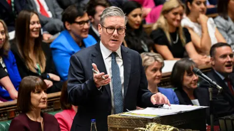 Reuters Sir Keir Starmer wearing a suit and speaking from the despatch box in the House of Commons, with Rachel Reeves sitting behind him 