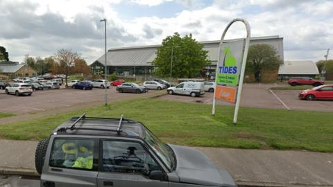 Tides Leisure Centre in Deal with a car park in front of the centre, and a green sign