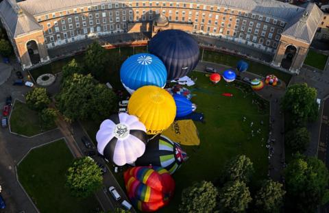 Hot air balloons are inflated on College Green in Bristol. The balloons are colourful and seen from overhead