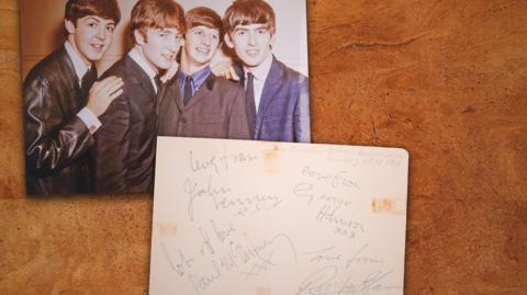 On the top right is a picture of the four Beatles in the mid-1960s. On the bottom right is a piece of paper signed "with love" by all four.