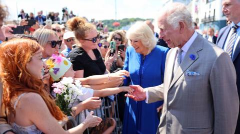 Queen Camilla and King Charles III meeting well-wishers as they arrive to attend the special sitting of the States of Deliberation, at the Guernsey Parliament in Saint Peter Port, Guernsey, during a two day visit to the Channel Islands.