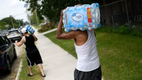 Houston residents carrying water from a distribution centre amid a deadly heat wave 