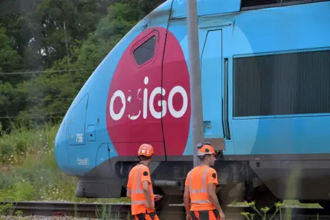 Rail workers in France stand beside a train