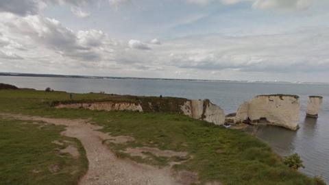 Path along the cliff edge with Old Harry Rocks on the right with sea and coastline in the distance