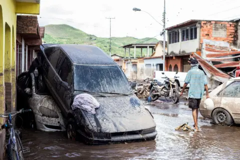 Reuters Muddy cars sit on top of each other in flooded streets