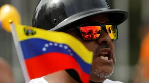 A motorcyclist holds a Venezuelan flag before the closing campaign rally of Venezuelan opposition presidential candidate Edmundo Gonzalez, in Caracas, Venezuela, July 25, 2024.
