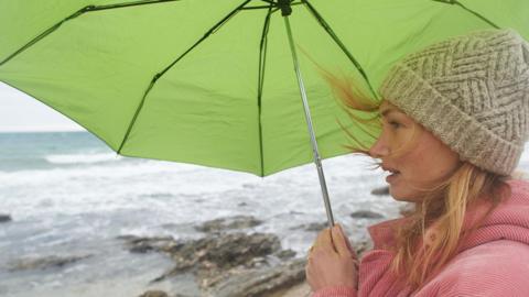 A woman with an umbrella by the sea - stock photo
