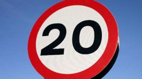 A 20 mile an hour speed sign with a blue sky background